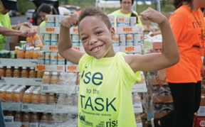   A little boy stands in front of canned goods on world hunger day.