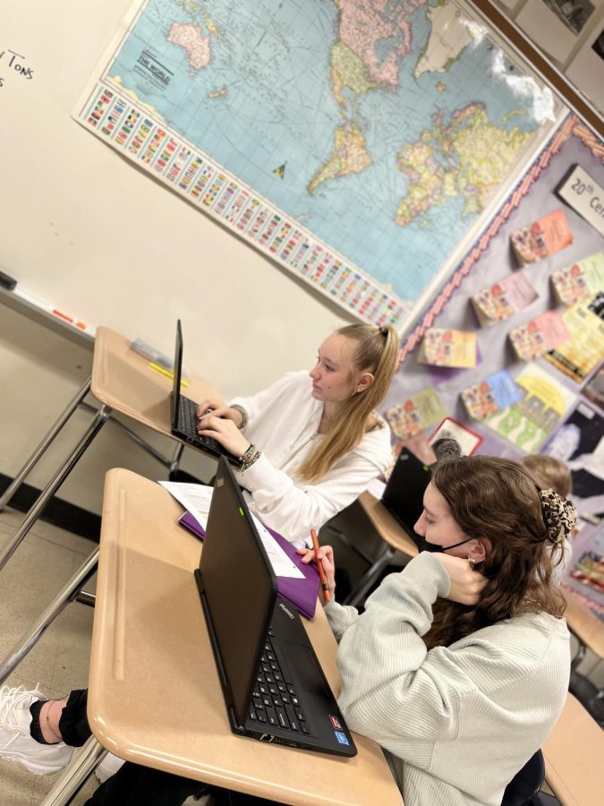 Ava Mumbauer (left) and her friend work together in social studies to learn about NATO and its impacts on the world.