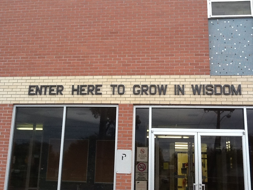 A building with the words Enter Here to Grow in Wisdom above the doors.