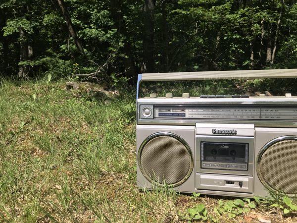 A boombox blasting music in front of the woods.