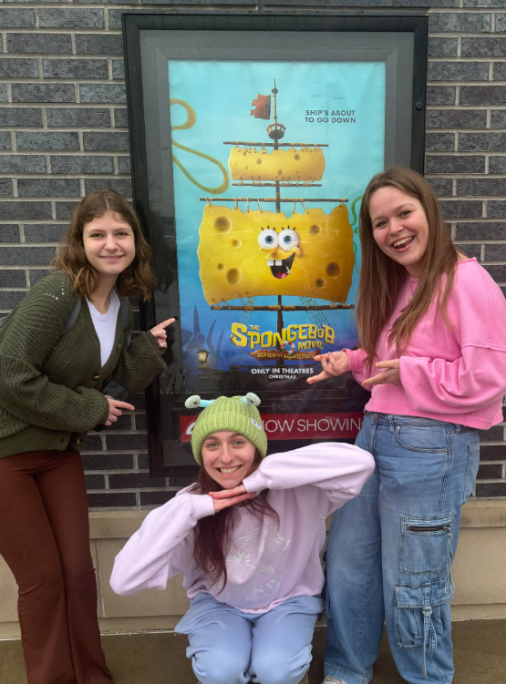 Riley Wayland, Maddie Warner, and Laura Walters posing in front of The SpongeBob Movie: The Search for SquarePants poster 