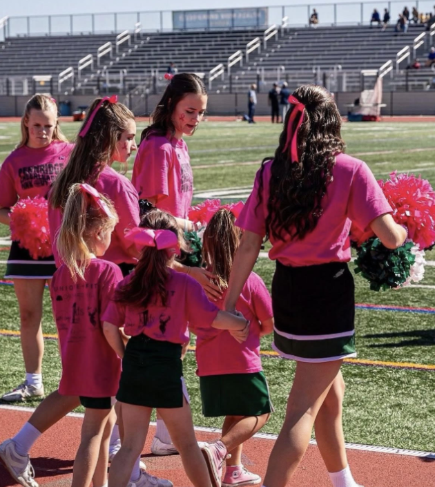 Peyton Hangey guiding young cheerleaders on the sidelines.