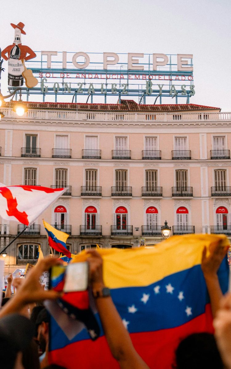 A crowd of Venezuelan citizens holding flags in front of a building.